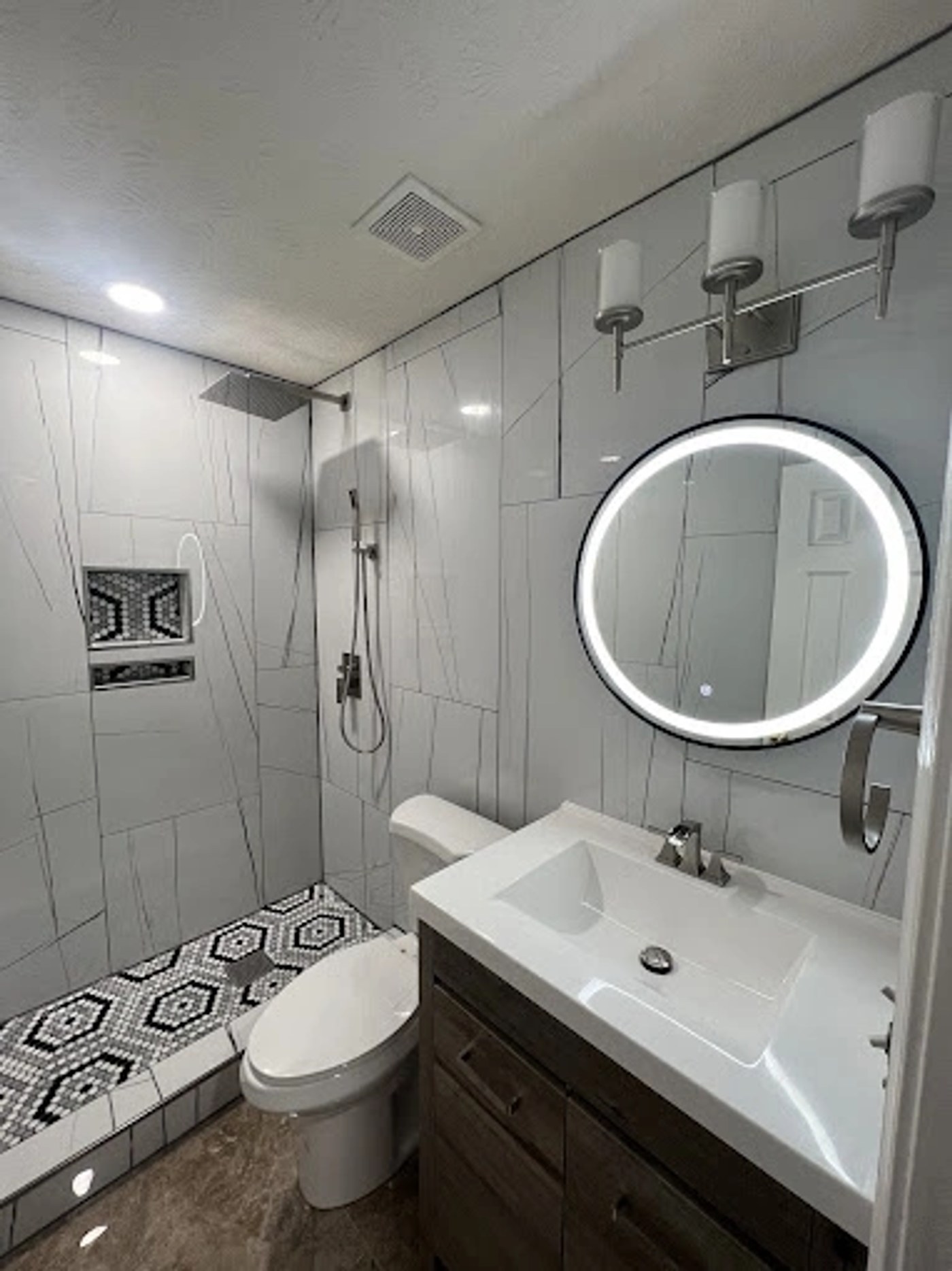 Remodeled bathroom with tiled shower and lighted mirror